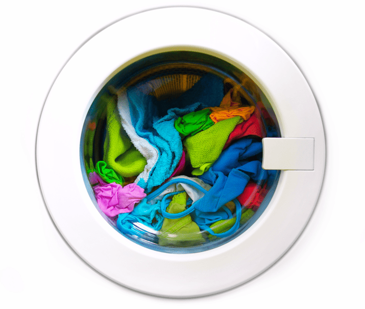 Cut out of the door of a washing machine full of colourful cloths